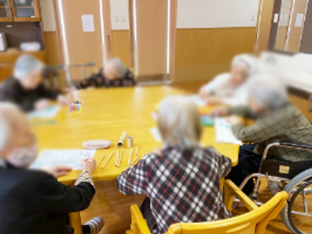 テーブルで活動する人々 ラウンジ 自然な光が差し込むラウンジで、机を囲みながら和やかに活動を楽しむ様子です。