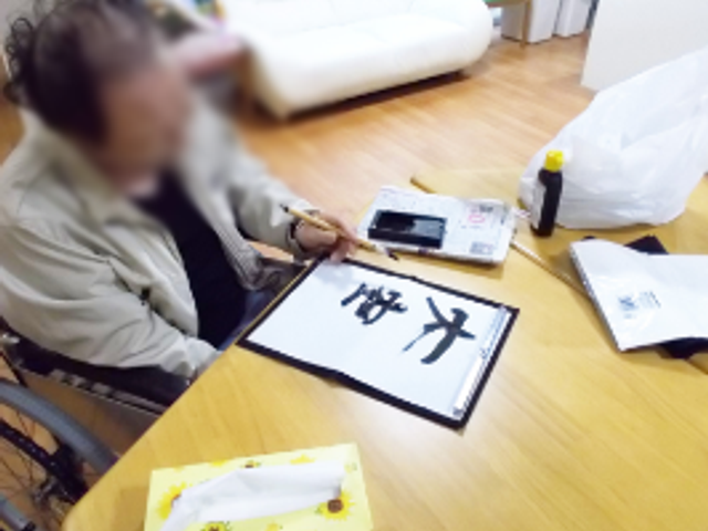 書道をする空間 ラウンジ 自然光が入る広々とした空間で、入居者が書道を楽しんでいます。リラックスした雰囲気が特徴です。