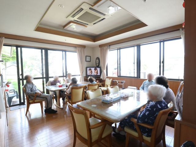 明るい共有ラウンジの様子 食堂 窓から差し込む自然光が心地良い、広々としたラウンジでの憩いの時間です。木製の椅子とテーブルが温かみのある雰囲気を演出しています。