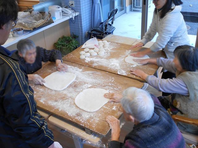 調理活動の風景 ダイニングルーム 入居者の方々が一緒にパン生地をこねています。楽しい交流を通じた活気ある時間を提供します。