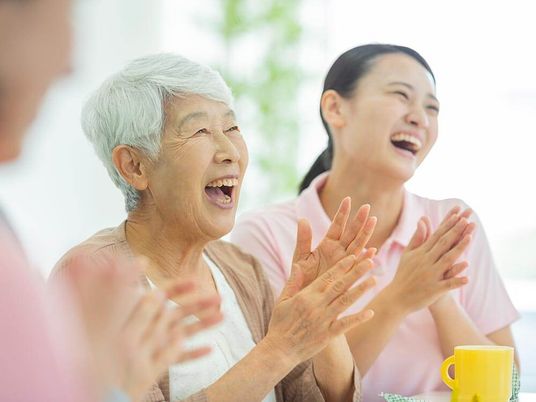 施設の写真 笑顔で拍手をする高齢女性と女性スタッフ