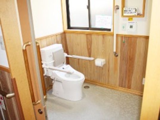 施設の写真 背もたれや手すりを設置したトイレは木材を使用した壁などがあり、圧迫感のない広い造り。