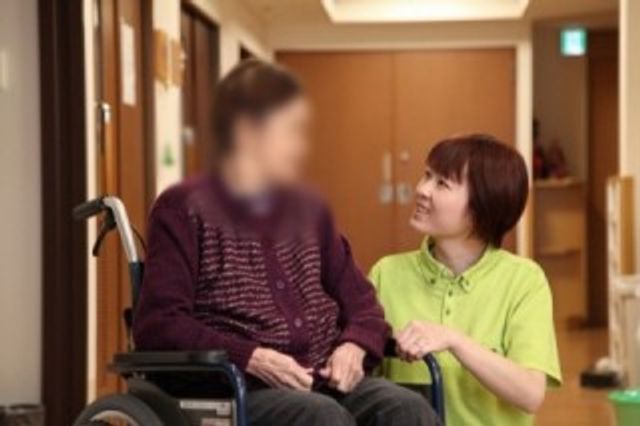 人と話す車椅子の女性 廊下 廊下 介護士が車椅子の利用者と談笑しています。温かい交流で心和む時間を提供します。