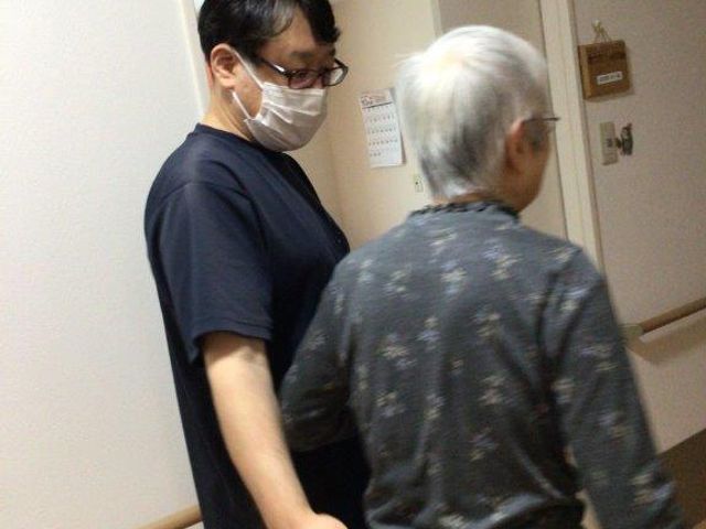 廊下を歩く人々 ケア スタッフが丁寧にサポートしながら、廊下を歩かれる様子です。安心して作業が行える環境ですね。