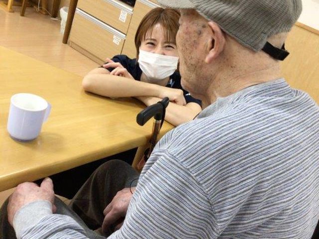 笑顔で対話する人々 ケア 笑顔あふれる交流スペースで、職員が利用者様と心温まる会話を楽しんでいます。コミュニケーションが活発な環境です。