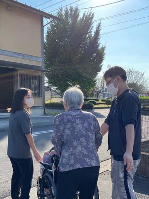 車椅子の高齢者と二人の介助者