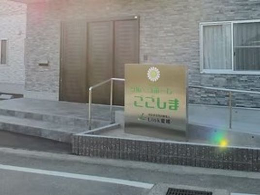 施設外観の看板前  