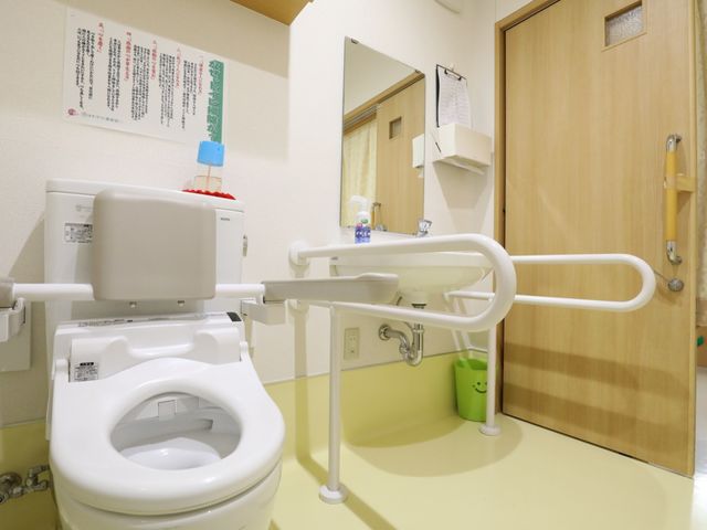 手すり付きの洗面所とトイレ トイレ 安全な手すりと広々としたスペースが特徴のトイレです。自立支援を考えた設計になっており、安心してご使用いただけます。