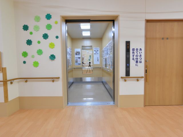 廊下と開いた扉の様子 エレベーター 床から壁まで明るく清潔感が漂う通路です。手すりが整った廊下は安全に配慮されております。