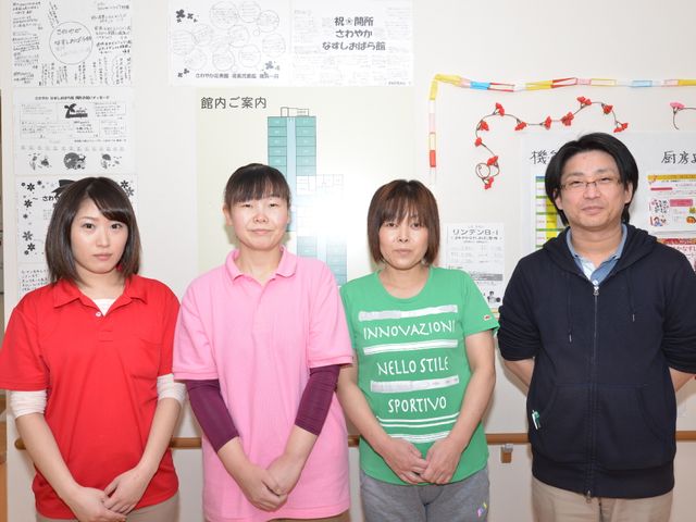 スタッフの集合写真 スタッフ 明るく和やかな表情を見せるスタッフ陣です。壁には多彩な掲示物があり、コミュニケーションの大切さを感じさせます。