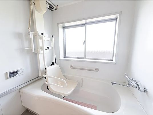 明るい浴槽と介助機器がある浴室  