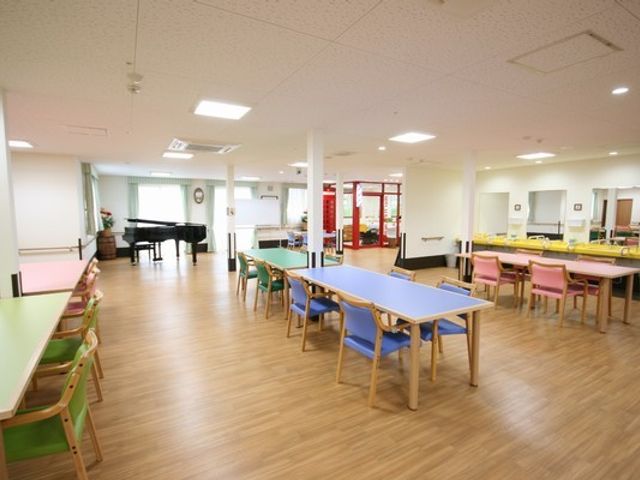 開放的なラウンジ ラウンジ カラフルなテーブルと椅子が設置された、広く明るい室内スペースです。ピアノも利用可能です。