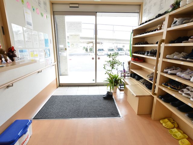 エントランスの靴棚とベンチ エントランスホール 全員のアクセスがしやすいように設計された明るい入口です。来訪の際には、安心感のあるこの空間から始まります。