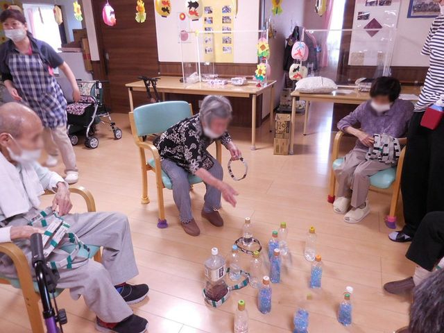 ゲームを楽しむ室内 多目的室 自然光が差し込む広々とした空間で、利用者の皆さんが輪になってゲームを楽しんでいます。