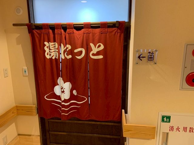 「湯けむり」のれん 浴室 落ち着いた色合いののれんが掛かった浴室の出入口です。温かみを感じさせるデザインが特徴です。
