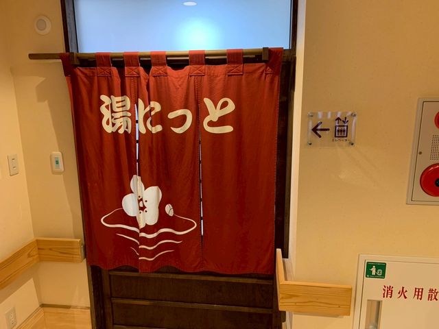 「湯けむり」のれん 浴室 落ち着いた色合いののれんが掛かった浴室の出入口です。温かみを感じさせるデザインが特徴です。