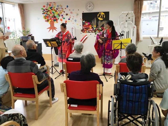 演奏イベントが行われる空間 多目的室 利用者の皆さんがくつろぐ中、音楽パフォーマンスが行われています。明るくリラックスできる空間です。