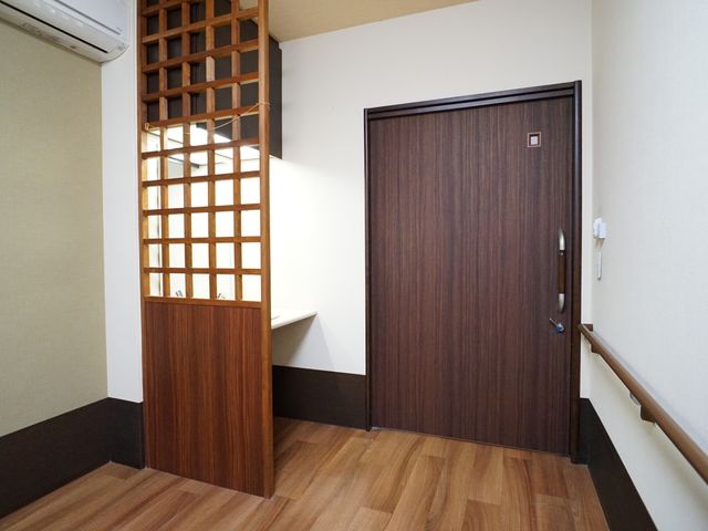 和風の格子窓と木製扉 居室 ゆとりある居室の一角は、和を感じさせるデザインが特徴です。和風の格子窓からは自然光がたっぷりと入り、温もりある空間を演出しています。