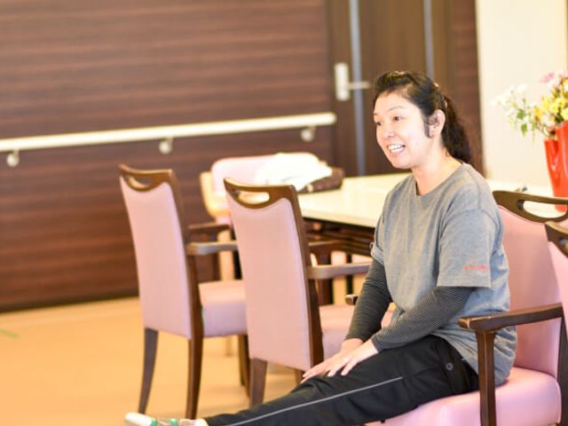 和やかなリビング リビング 笑顔を浮かべて椅子に座る方が、落ち着いた雰囲気のリビングでくつろいでいます。会話や休憩に最適な場所です。