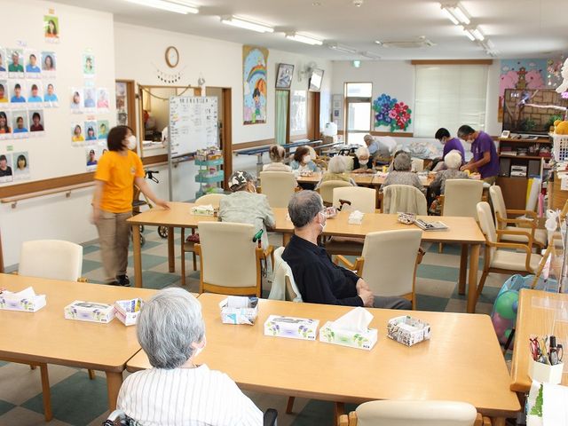 人々が集まる共用スペース 多目的室 広々とした多目的室で、利用者が和やかに交流しています。自然光が差し込み、明るい空間が広がっています。