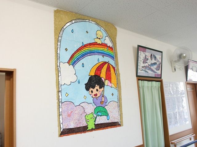 壁の装飾がある廊下 廊下   明るい廊下の壁に、手作り風の大きな装飾が飾られています。季節感のある掲示で、働く場のあたたかい雰囲気が伝わります。