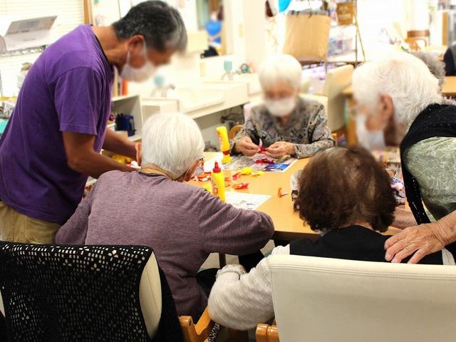 高齢者との交流の様子 ラウンジ 広々としたラウンジで、高齢者が楽しそうに手作業に集中しています。スタッフも一緒に活動しています。
