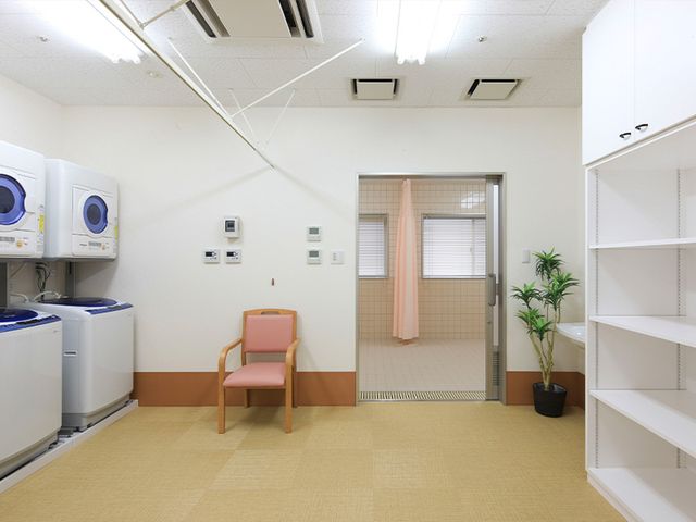 広い洗濯設備のある部屋 コインランドリー 広々とした空間に設置された洗濯機で、利用者の方々が自由に洗濯を行えます。シンプルで清潔感のある部屋です。