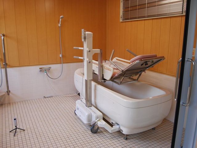 機械浴設備の浴室 浴室 介助がしやすい構造になっている浴室です。温かみのある木目調の壁が特徴的です。