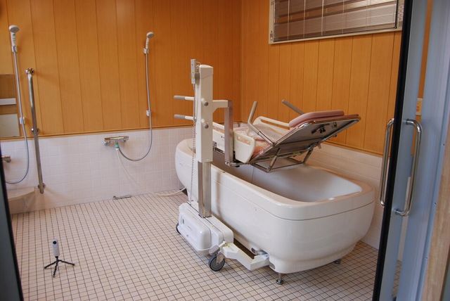 機械浴設備の浴室 浴室 介助がしやすい構造になっている浴室です。温かみのある木目調の壁が特徴的です。