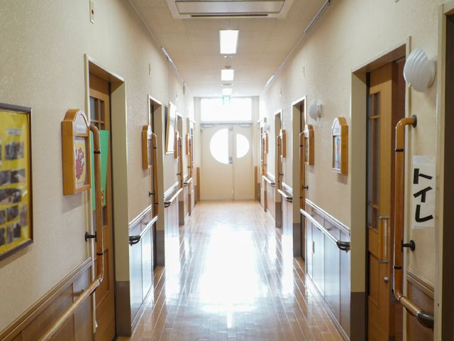 照明の明るい廊下 廊下 手すりが備えられた、ゆったりとした通路です。掲示物が飾られ、温かみのある雰囲気を醸し出しています。