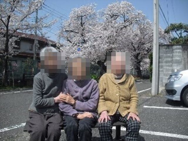 桜並木と談笑する人々 日常風景 穏やかな桜並木の下、笑顔で語り合う三人が心温まる雰囲気を醸し出しています。