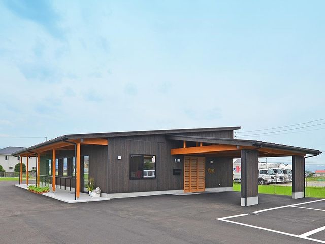 平屋の建物外観 外観   木目調の落ち着いた平屋建てで、広い駐車スペースがあります。屋根付きの出入り口があり、雨の日も移動しやすそうです。
