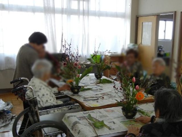 花作りを楽しむ居室 居室 入居者の皆さんが集まり、花を活けています。自然光が差し込む明るい雰囲気です。