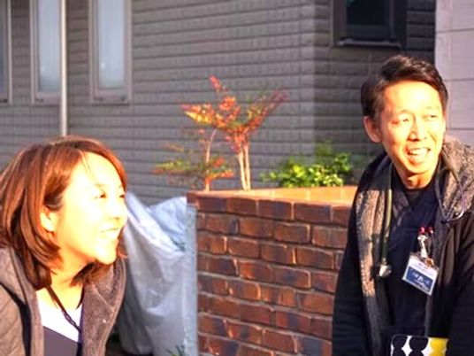 笑顔の職員二人と外壁  