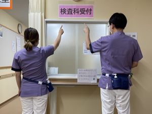 検査科受付で案内する職員  