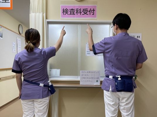 検査科受付で案内する職員  