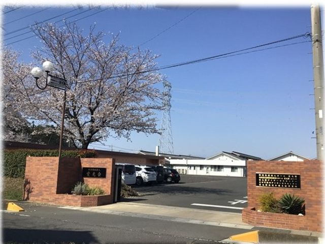 桜のある施設外観 外観   広い駐車場とレンガ調の門が見える落ち着いた外観です。春らしい桜があり、明るい雰囲気が伝わります。