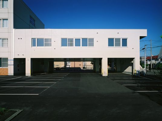 明るい外観と駐車場のある建物  