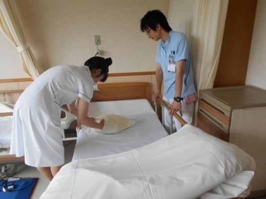 居室でベッドを整える職員  