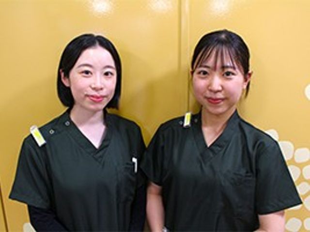 スタッフ2人が並ぶ前景 スタッフイメージ   同じ制服を着たスタッフの方が2人並んで写っており、落ち着いた表情で案内役の雰囲気が伝わります。就業時のイメージを持ちやすい一枚です。