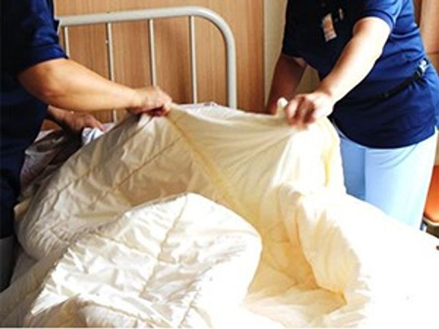 ベッド周りの整備 居室   職員の方がベッドメイキングを行っている様子です。入居者の方が快適に過ごせるよう、日々の整備が丁寧に行われています。