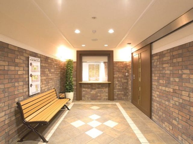 ベンチが置かれた廊下 エントランス 温かみのある照明が特徴の廊下では、掲示物を見ながら一息つけるベンチが設置されています。