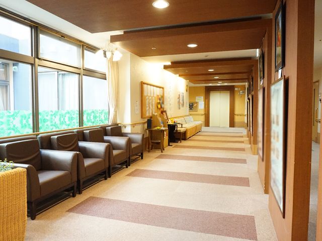 明るい共有ラウンジの様子 廊下 ゆとりある空間のラウンジは、日常の憩いや来訪者との歓談に最適です。木目調のインテリアが温かみを感じさせます。