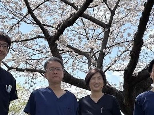 スタッフが桜の下に並ぶ庭  