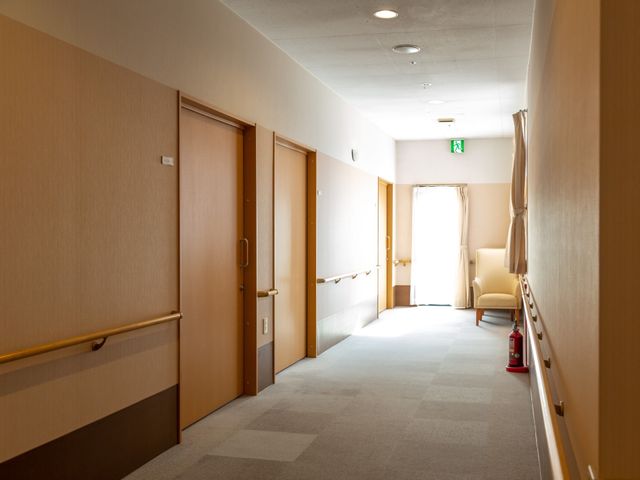 廊下の端にある椅子 廊下 椅子と手すりが設置された清潔感のある通路です。明るい光の中、静かなひとときを過ごせるスペースがあります。