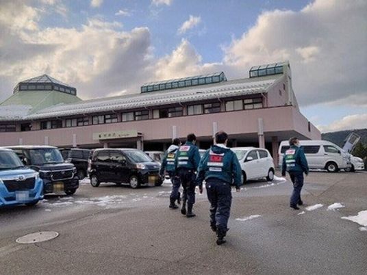 施設前を歩く職員と駐車場  