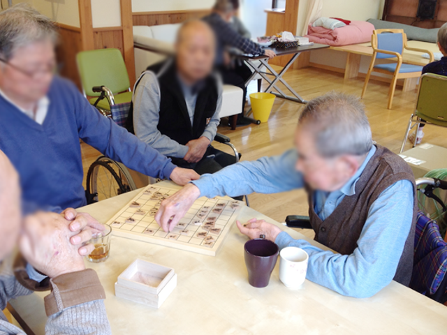 将棋を楽しむ室内 リビング 広々としたリビングで、住民が楽しそうに将棋を楽しんでいます。自然な交流が生まれる空間です。