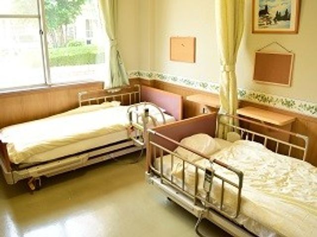 明るい居室の二床室 居室   自然光が入る明るい二床室です。ベッドの間に家具が置かれ、落ち着いて過ごしやすい空間です。