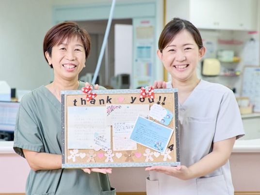 笑顔の職員と掲示板のフロント  