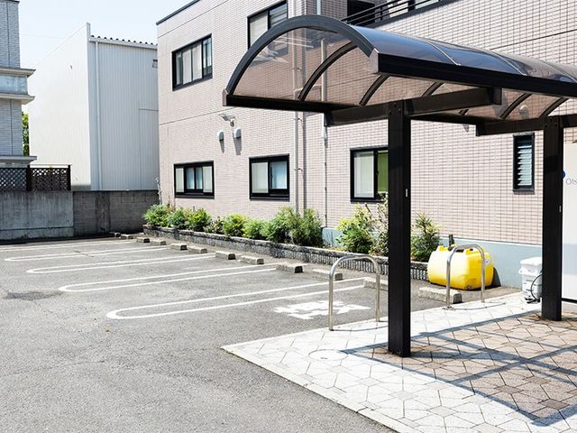 建物前の駐車場外観 外観   建物前に駐車スペースが整えられており、来訪時の車の出入りがしやすそうです。雨よけのある屋根付きスペースも見えます。